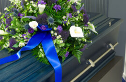 A blue coffin in a morgue with a flower arrangement