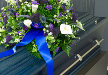 A blue coffin in a morgue with a flower arrangement