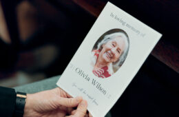 Funeral, photo and senior woman death in church with respect and farewell memorial. Goodbye, hands and chapel with sadness and mourning of grandmother with information and picture of elderly person